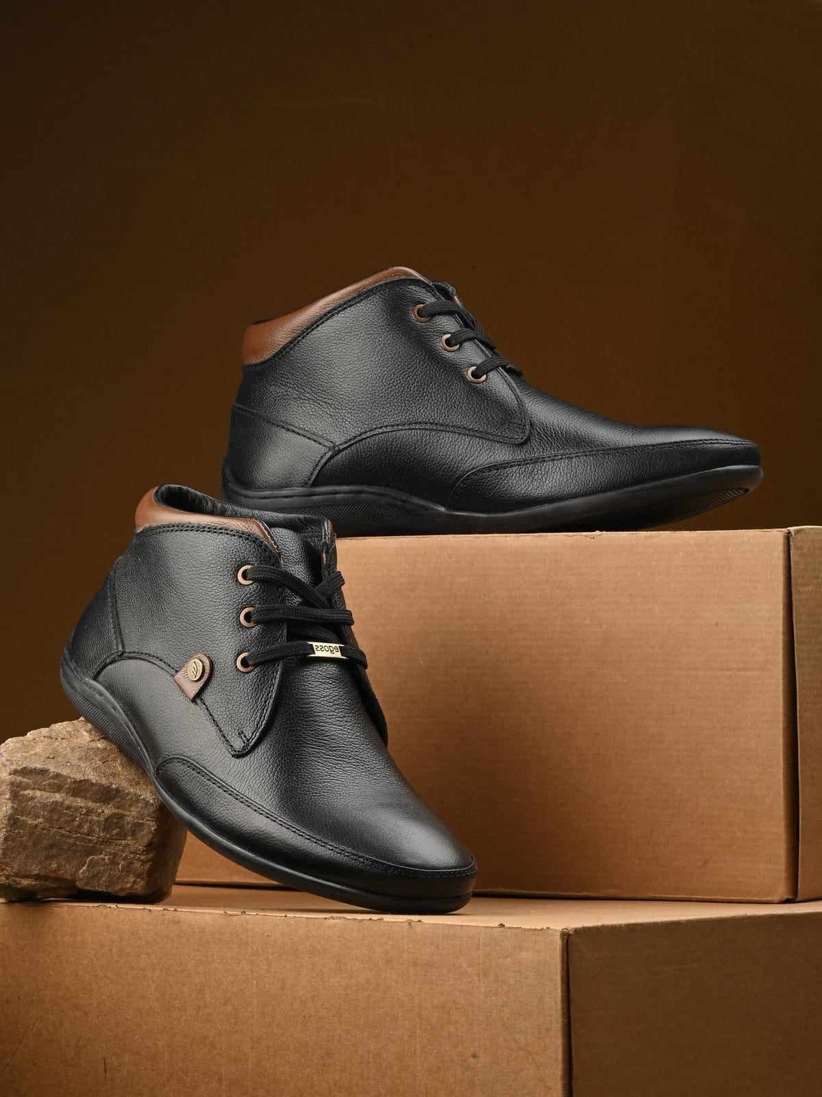 Black leather shoes with brown accents on a cardboard box against a brown background