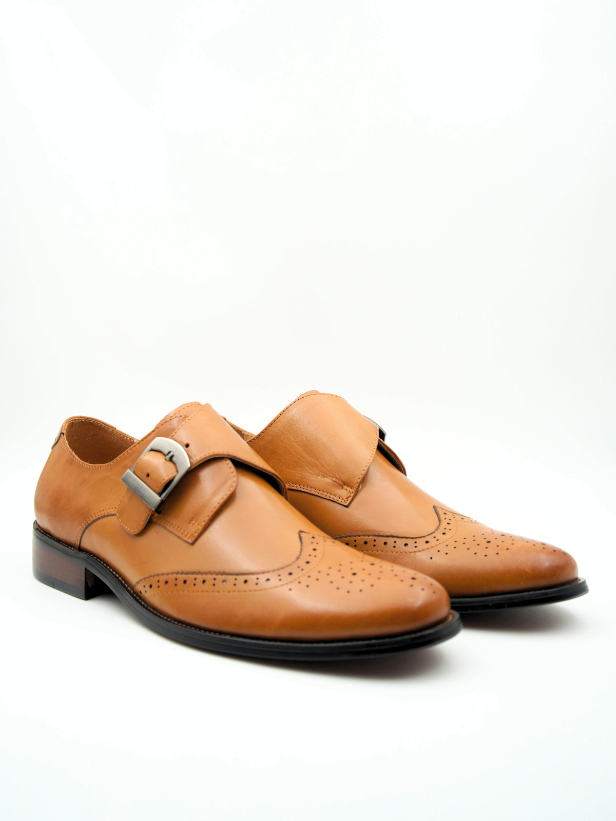 Pair of tan leather shoes with buckles on a white background