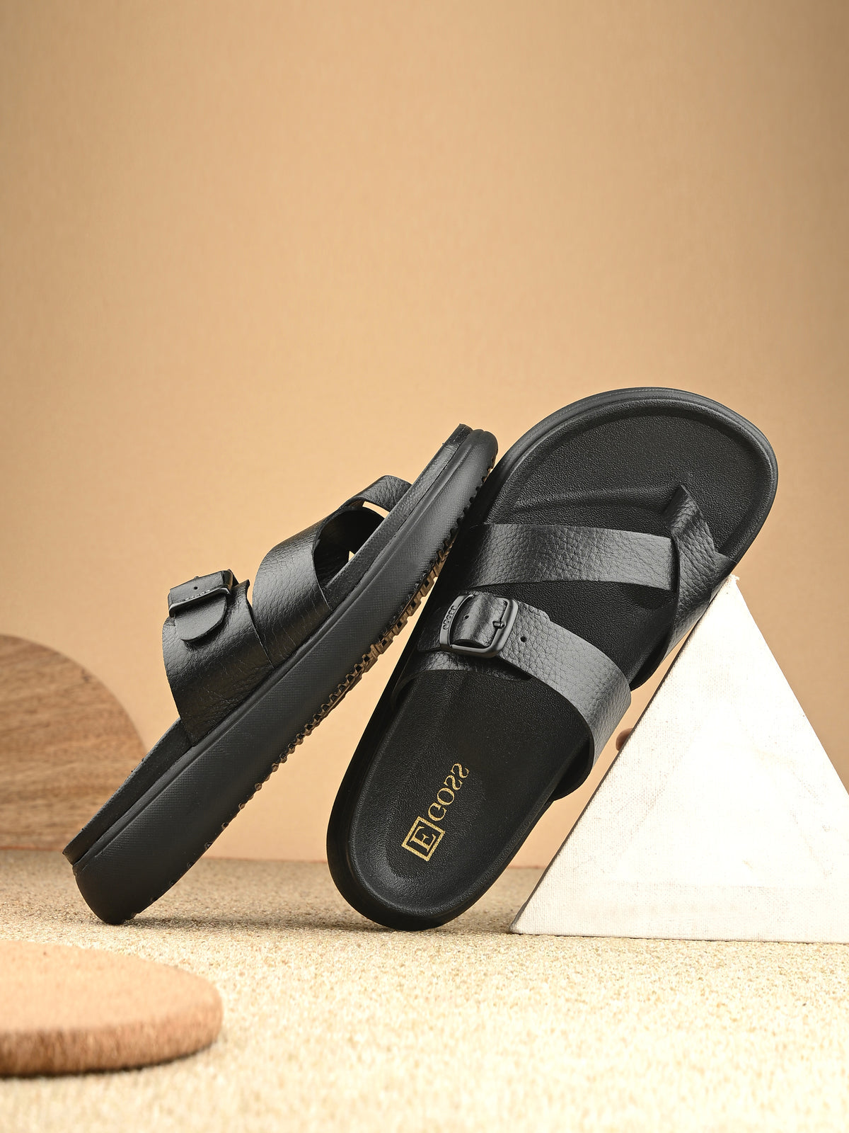 Black sandals with a brand logo on a beige background