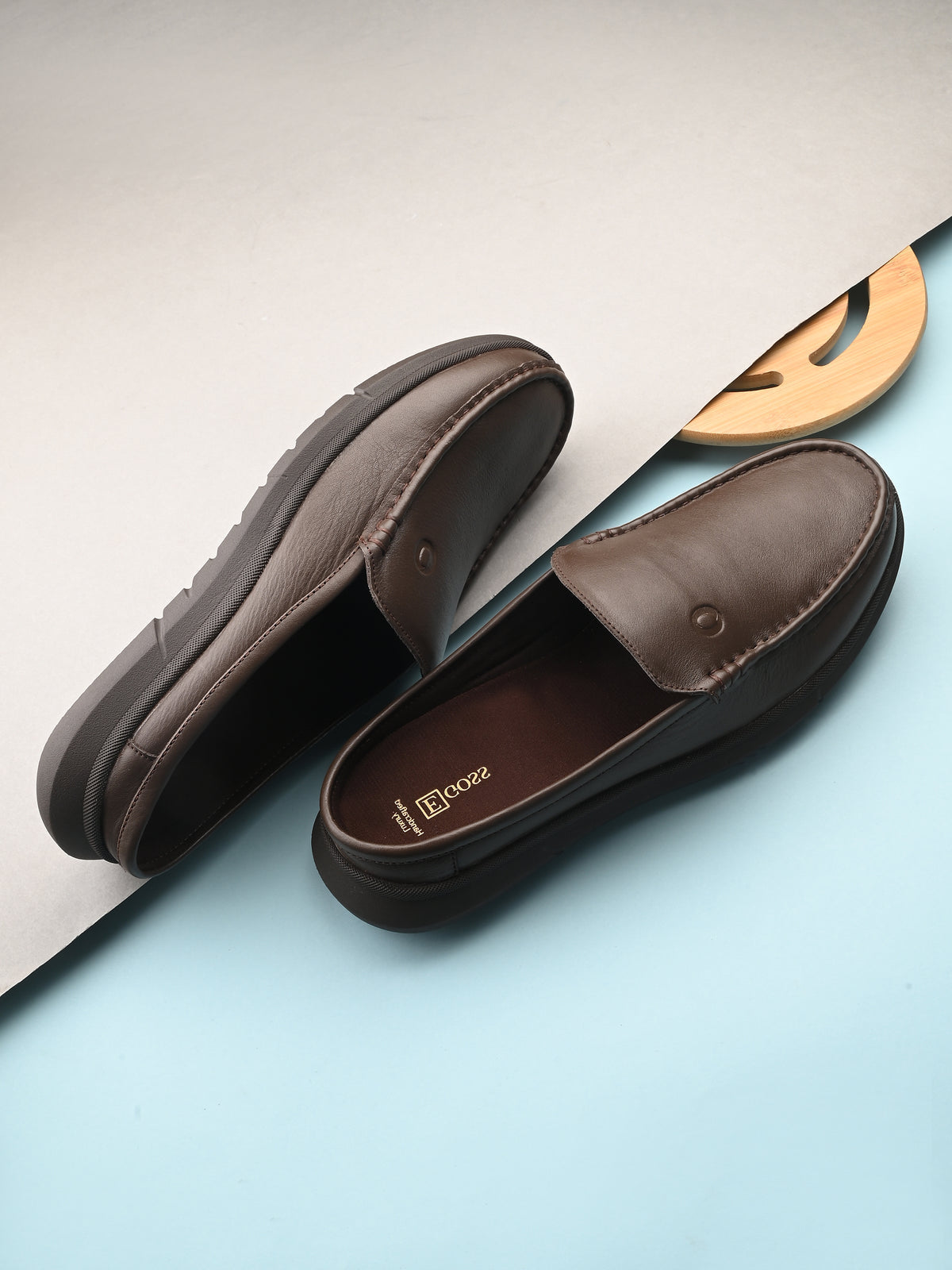 Brown loafers on a light blue surface with a white paper background.