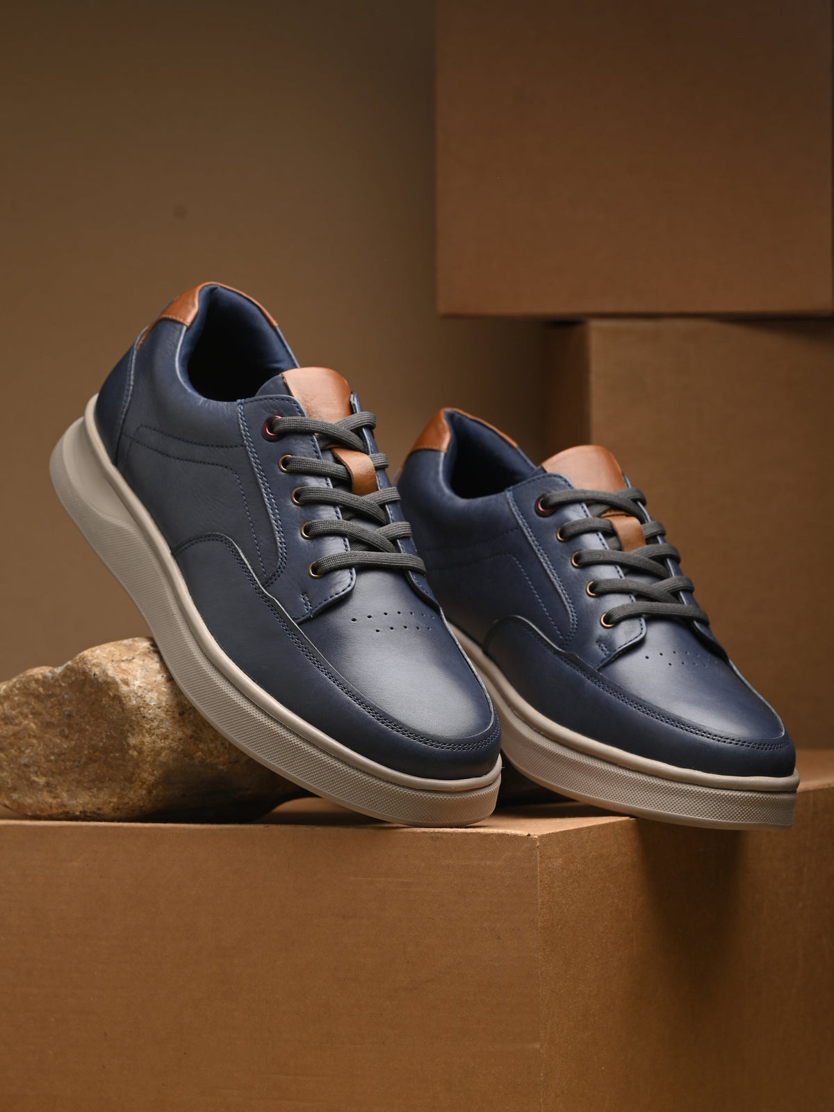 Pair of blue sneakers with white soles on a cardboard box.