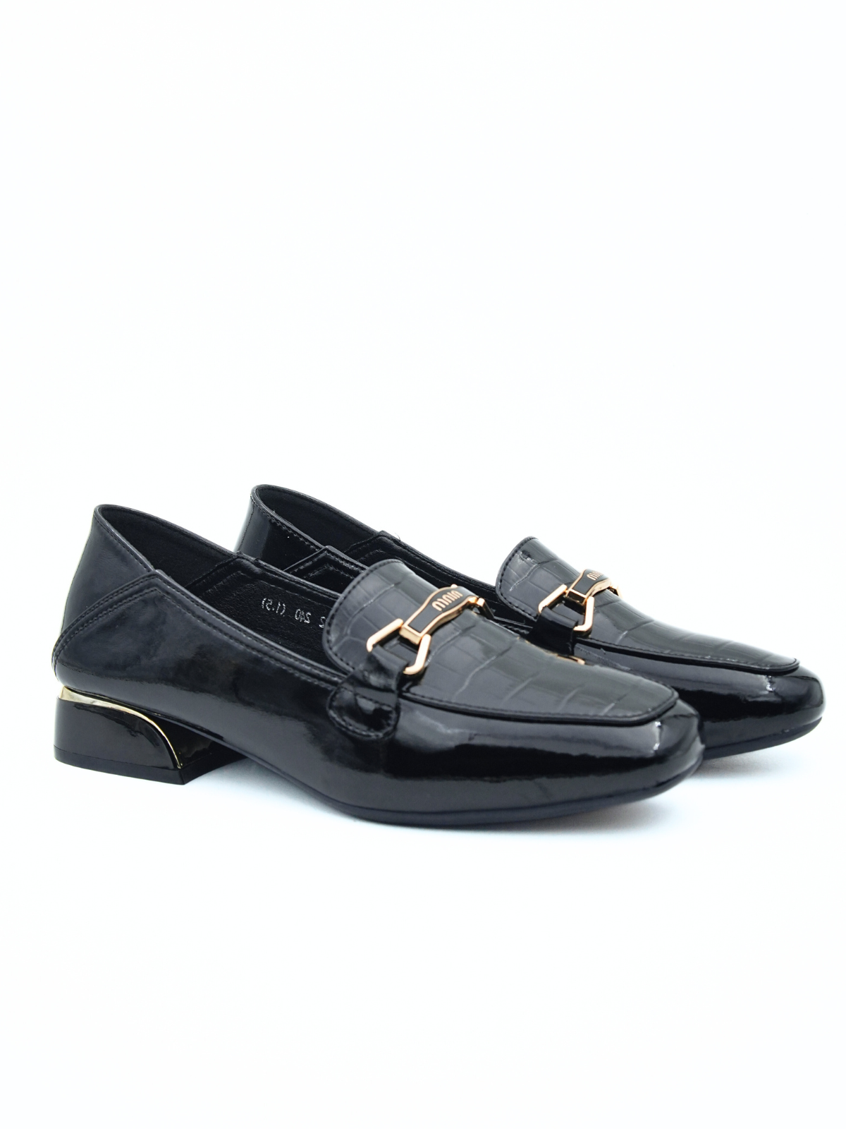 Pair of black patent leather loafers with gold buckles on a white background