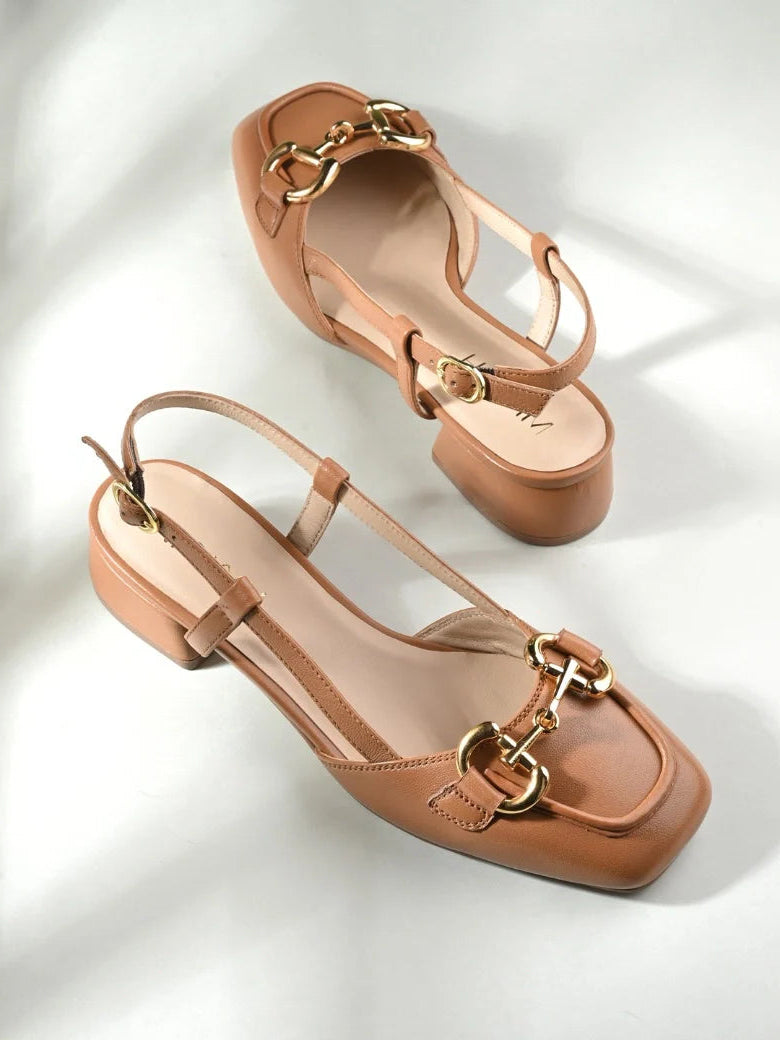 Pair of tan sandals with gold buckles on a light background